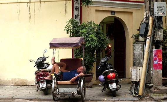 Un chauffeur de cyclo-pousse s'endort dans un coin du vieux quartier d'Hanoi